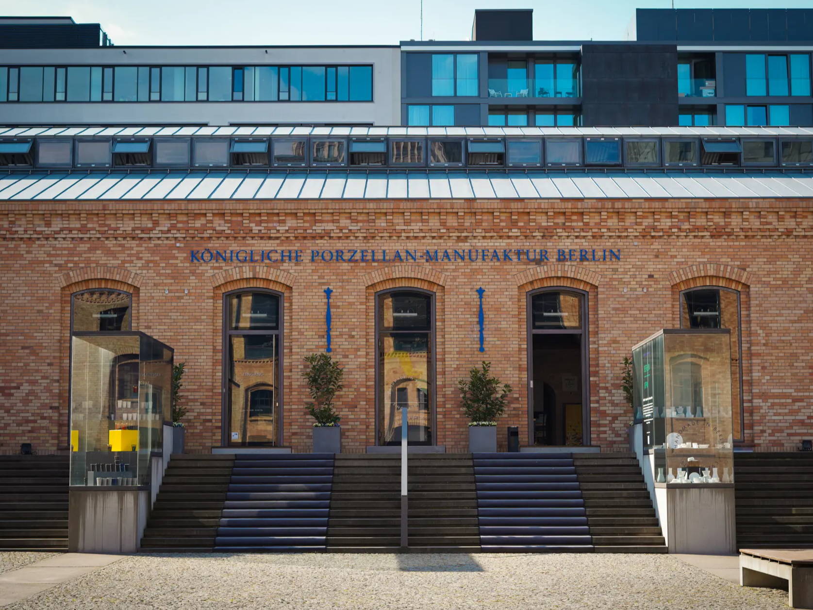 Eingang eines Backsteingebäudes mit modernem Oberbau und Glastüren.