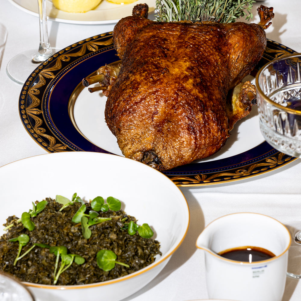 Canard rôti, servi avec des légumes verts et une sauce, présenté dans une assiette décorative.