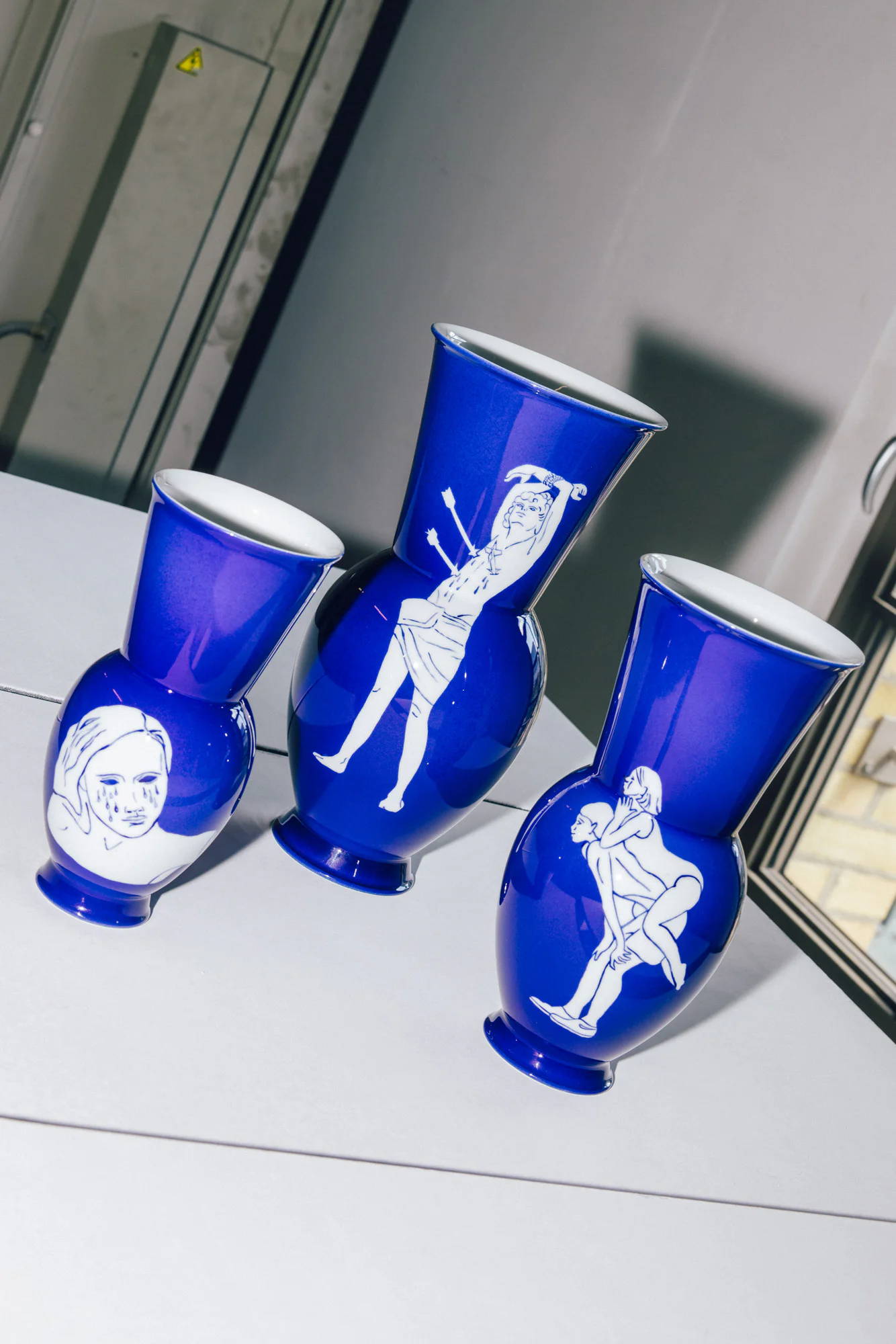 Drei blaue KPM Vasen mit dekorativen Illustrationen auf jeder Vase.