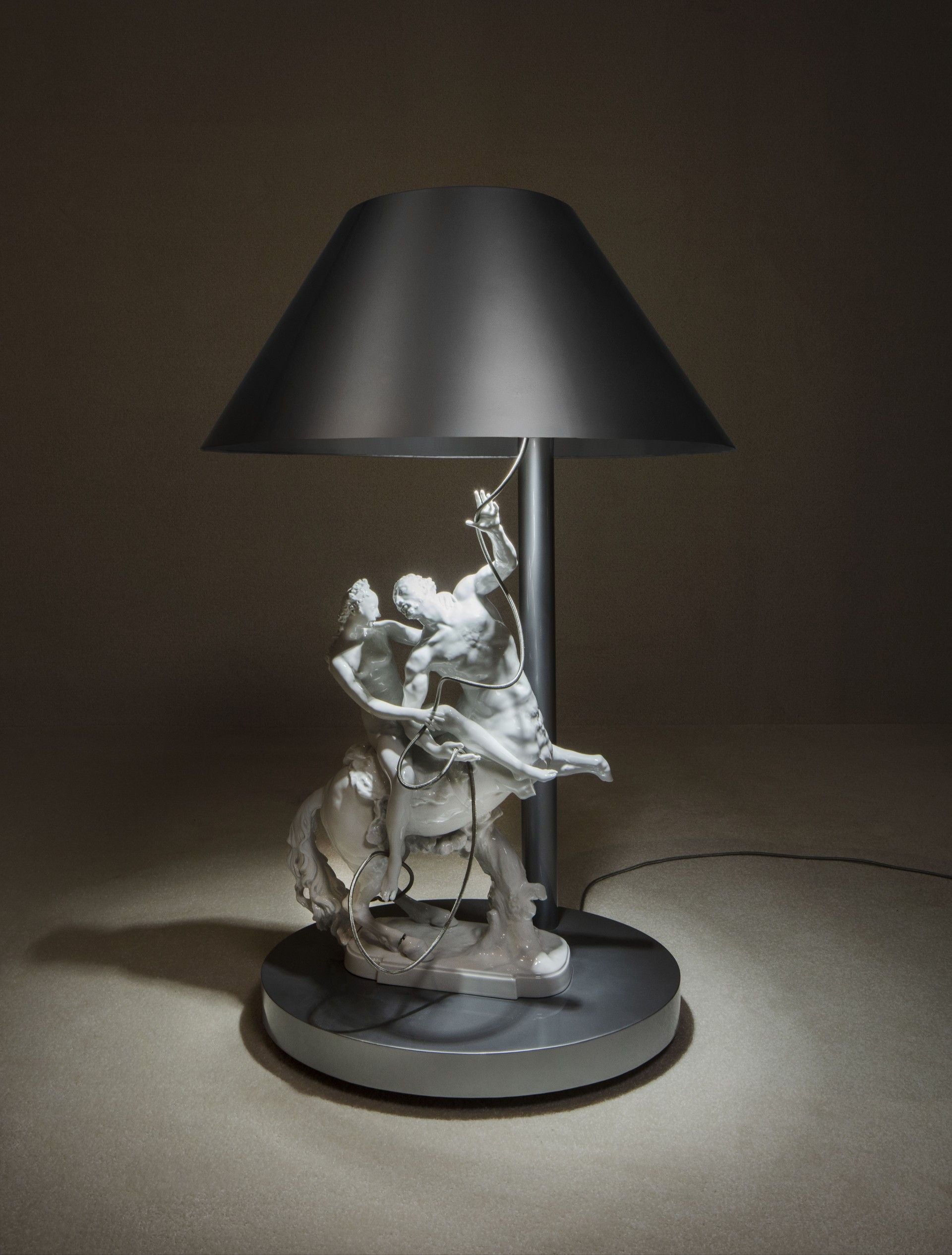 A lamp featuring a sculpted horse and rider base with a black shade.