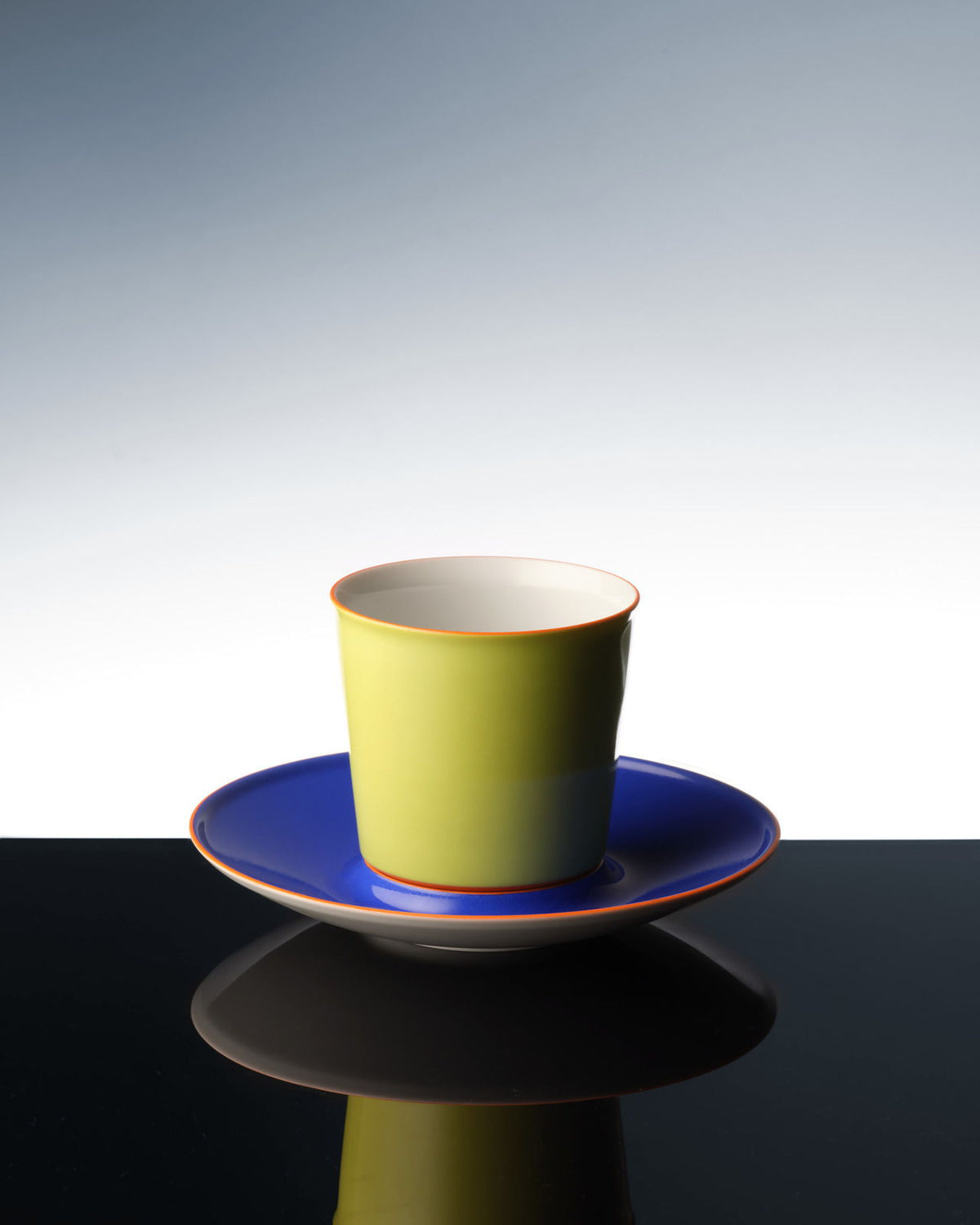 Eine bunte Flugzeugtasse, die sich auf einer dunklen Oberfläche spiegelt.