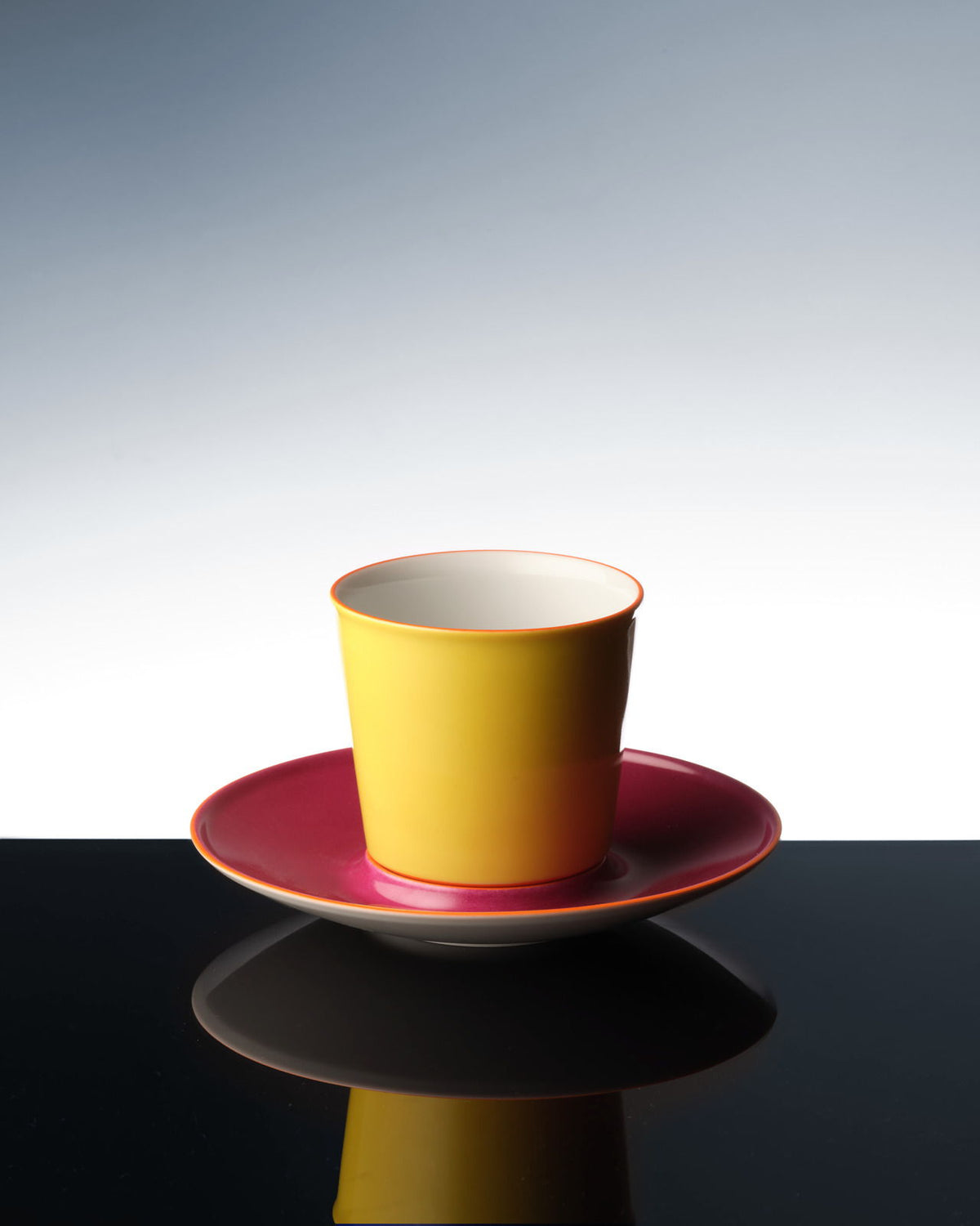 Eine bunte Flugzeugtasse, die sich auf einer dunklen Oberfläche spiegelt.