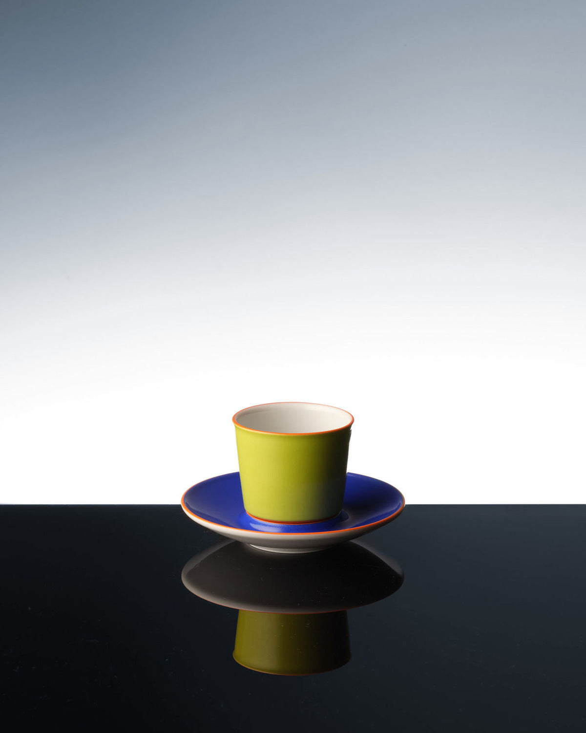Eine bunte Flugzeugtasse, die sich auf einer dunklen Oberfläche spiegelt.