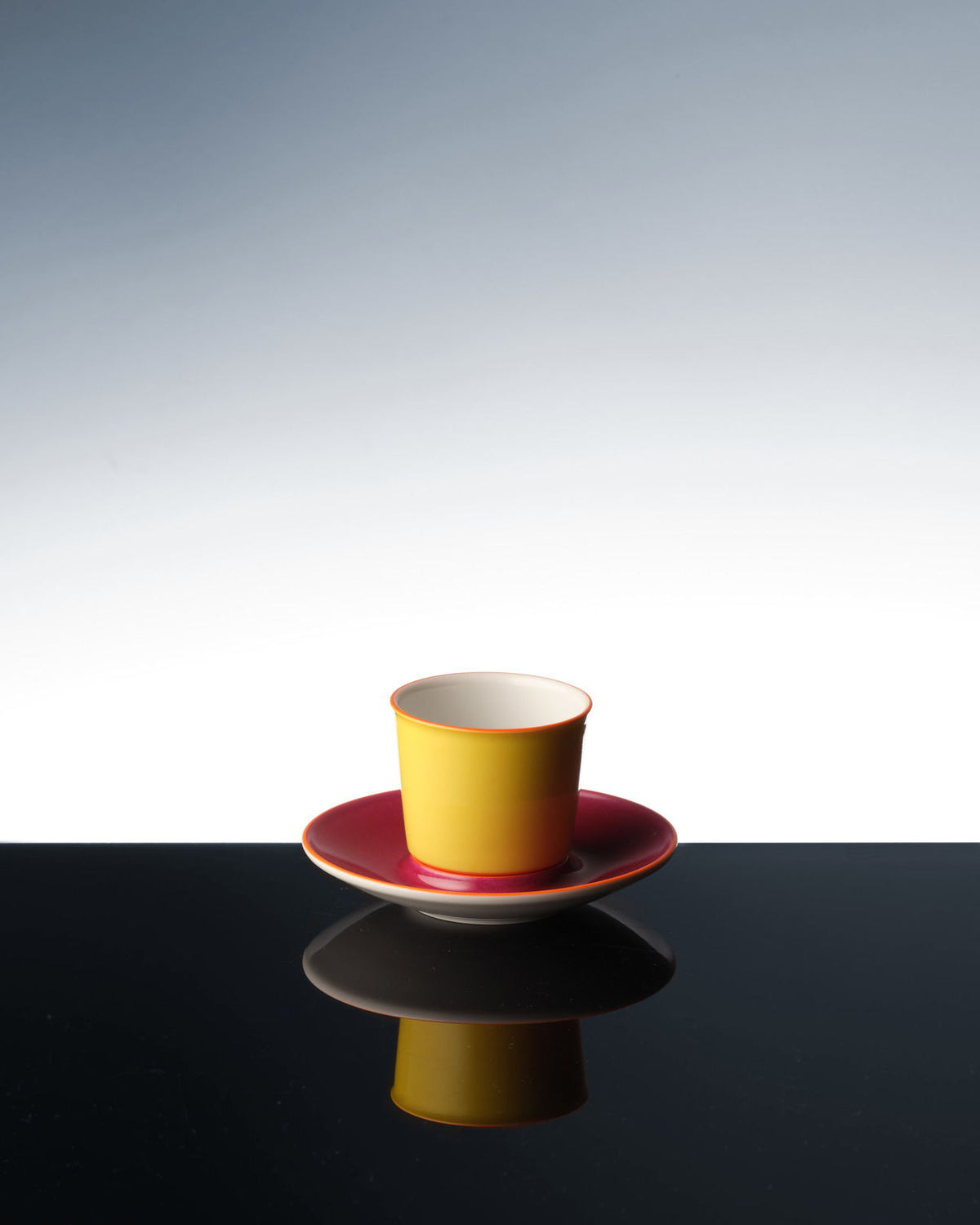 Eine bunte Flugzeugtasse, die sich auf einer dunklen Oberfläche spiegelt.