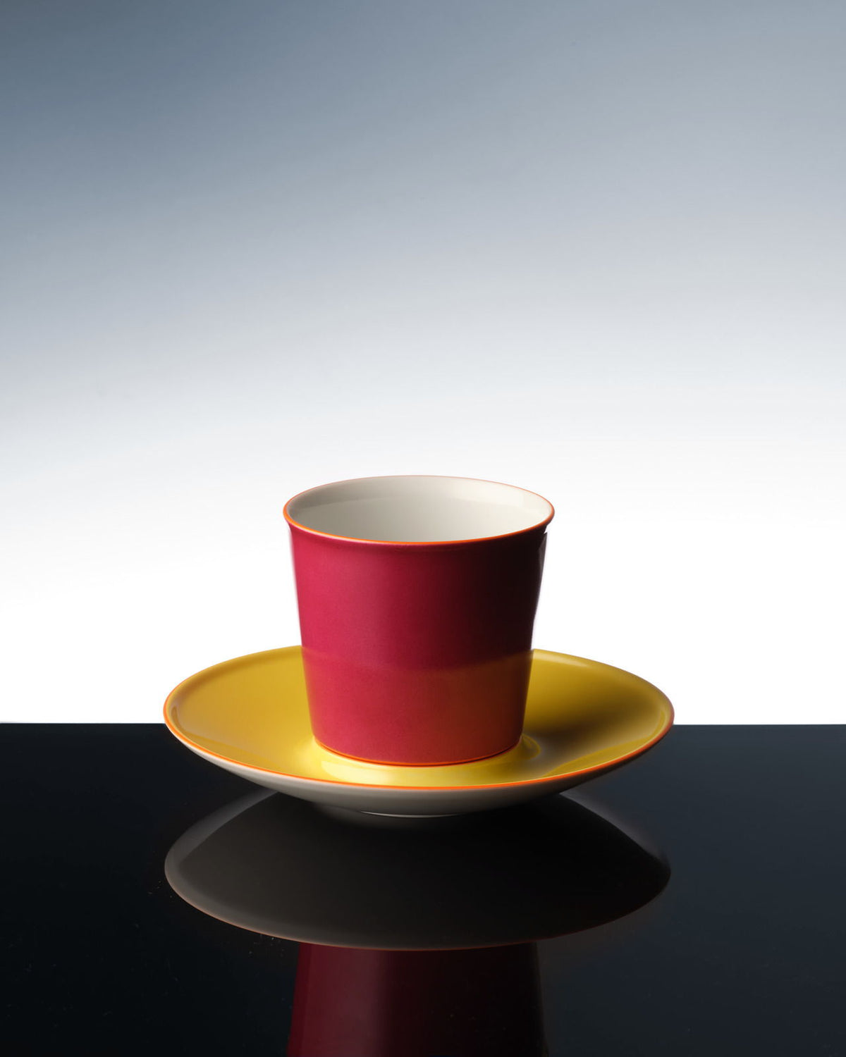Eine bunte Flugzeugtasse, die sich auf einer dunklen Oberfläche spiegelt.