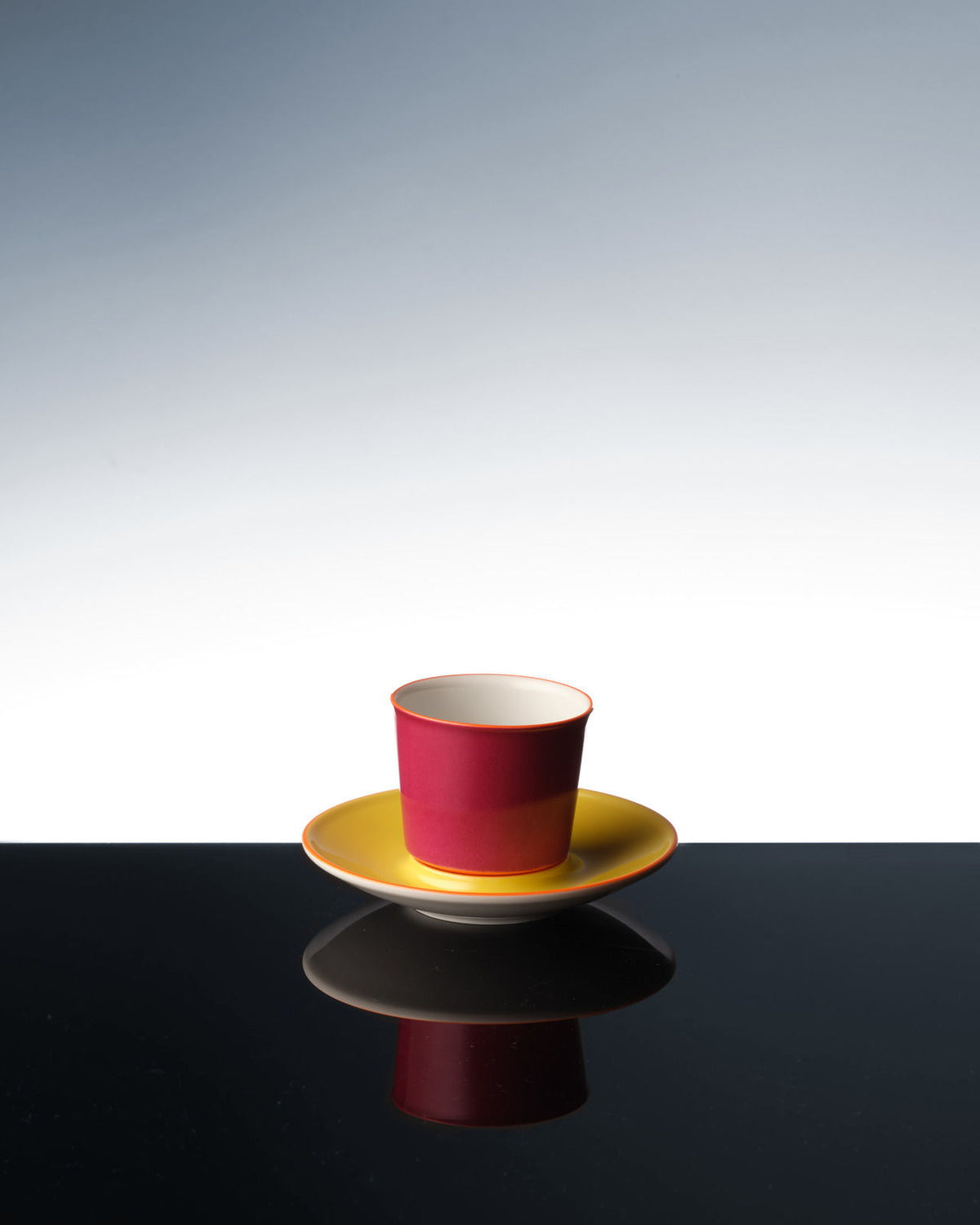 Eine bunte Flugzeugtasse, die sich auf einer dunklen Oberfläche spiegelt.
