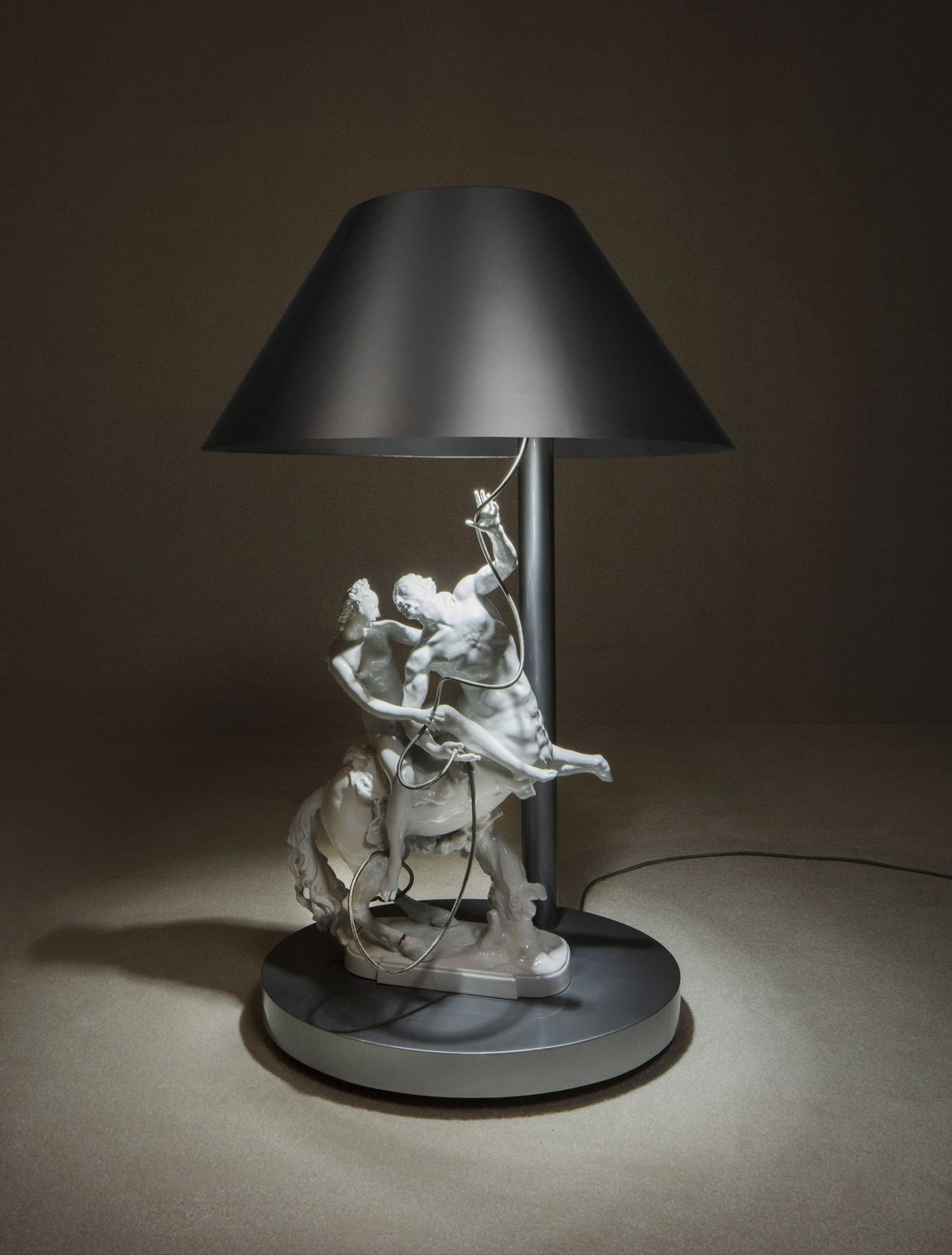 A lamp featuring a sculpted horse and rider base with a black shade.