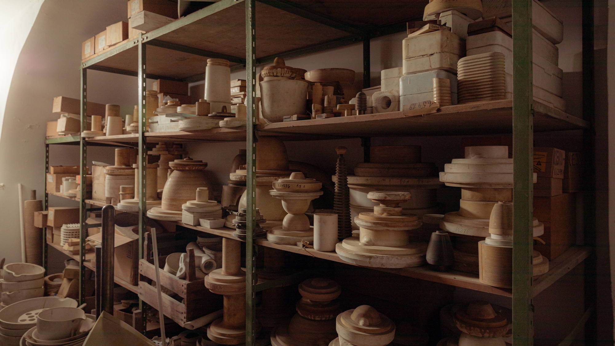 Des étagères contenant diverses pièces de poterie et d'objets en céramique dans un local de stockage.