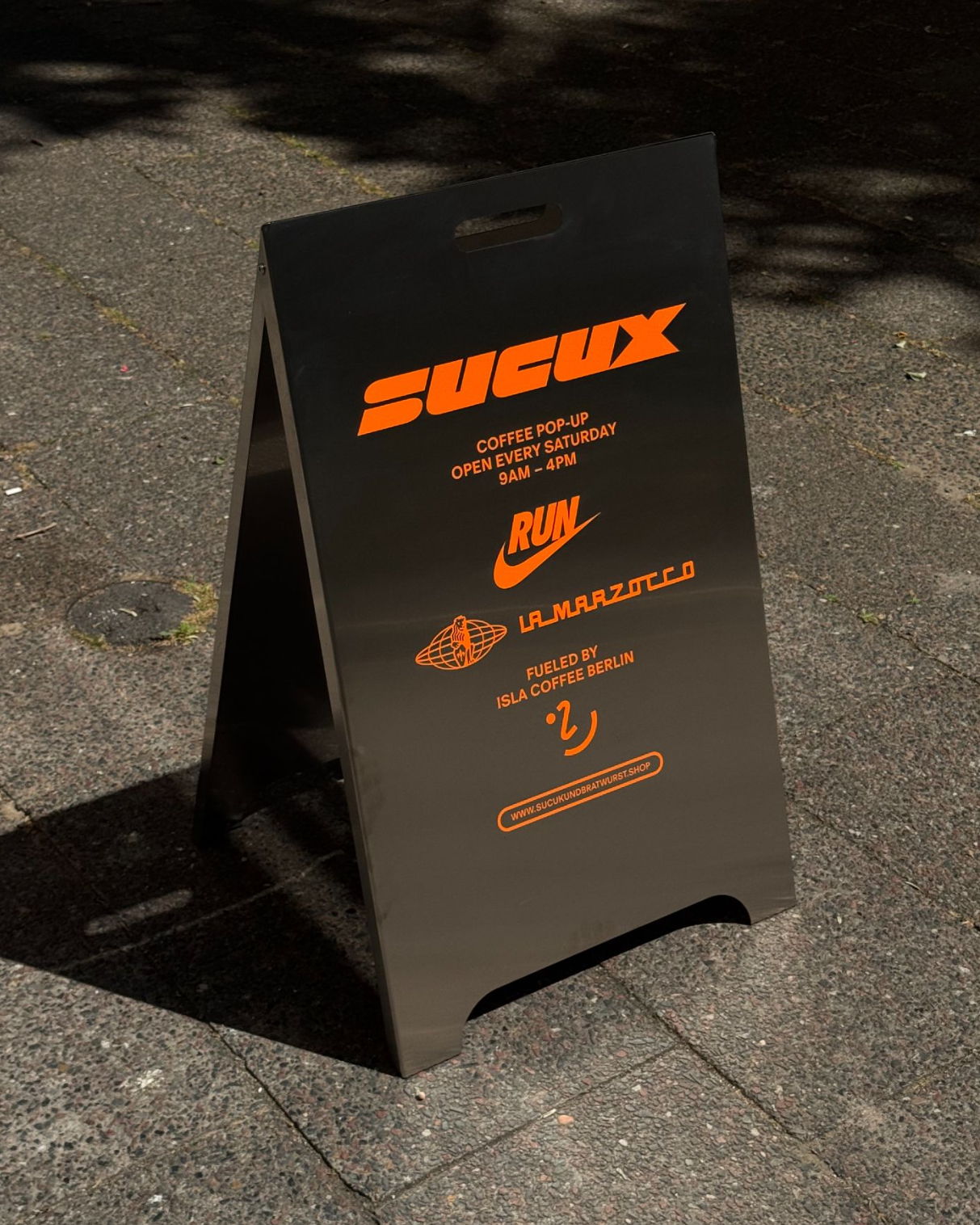 Schwarzes Schild mit der Aufschrift „SUCUX“ und Logos verschiedener Marken.